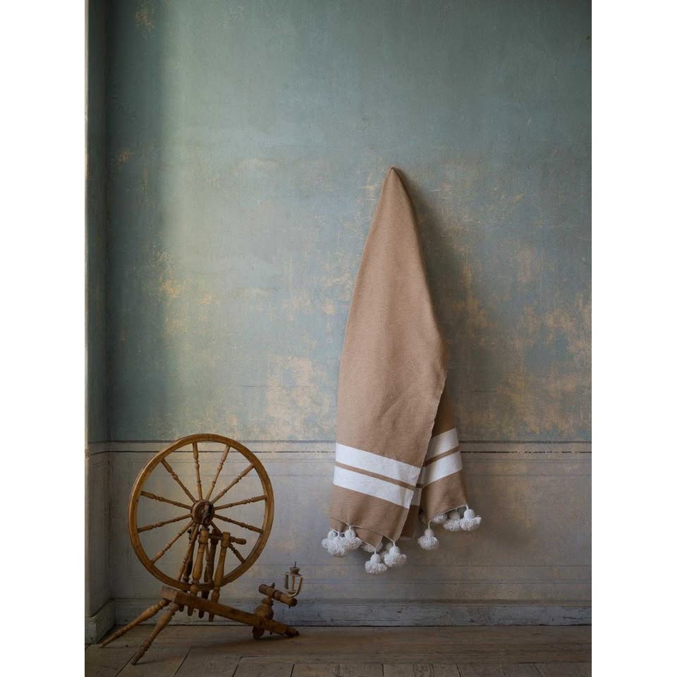 Manta beige con rayas y pompones blancos